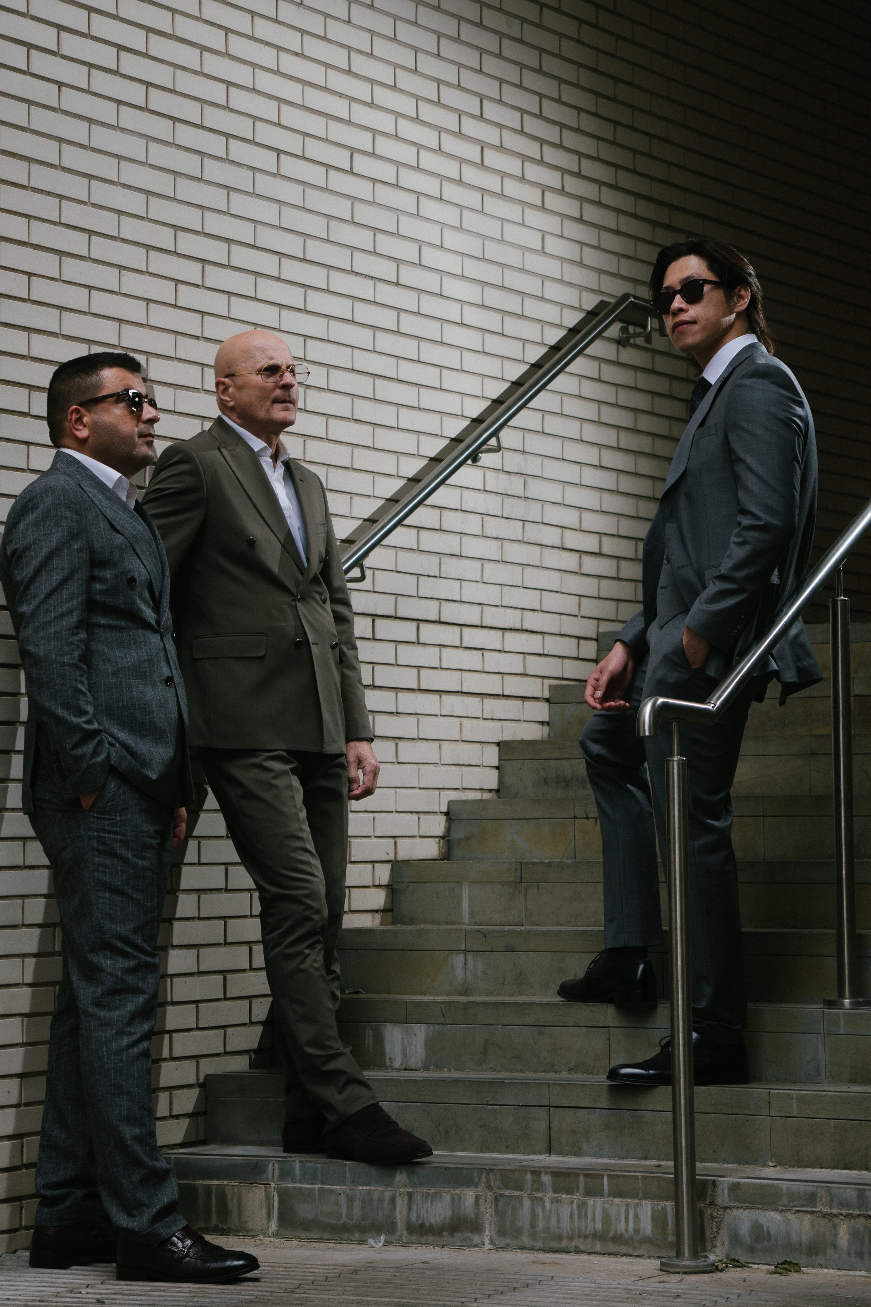 Three men in suits against brick wall